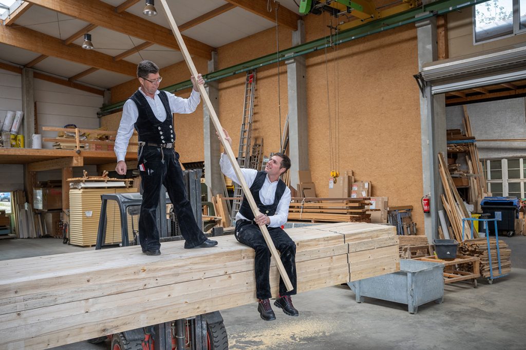 Die Geschäftsführer Klaus Frank und Martin Frank in der Werkstatt der Firma, beide halten gemeinsam eine lange Holzleiste.